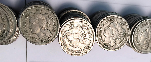 [photo: Close-up of nickel three-cent pieces sorted by date]